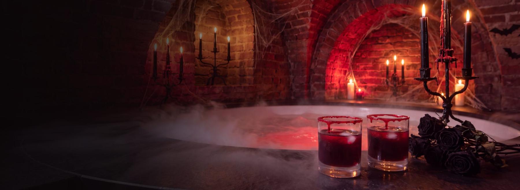 Vířivka v cihlových katakombách s mlhou, černými svícemi a dvěma tmavě červenými nealko drinky
